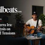 Brazilian musician in a studio with a world map backdrop, illustrating geopolitics and music.